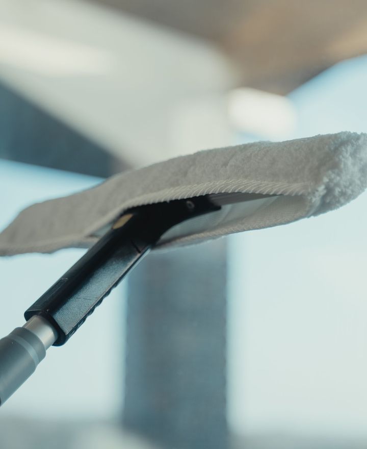 Close-up of a water-fed pole brush resting against clean glass